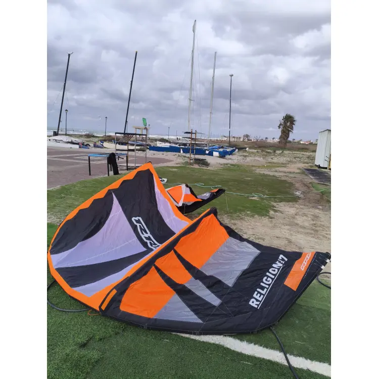 קייט משומש RRD Religion 7 מטר בצבעי שחור-כתום על הדשא בחוף הים