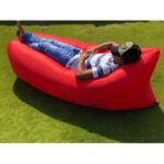 אדם נח על ספת אוויר מתנפחת אדומה של Super Boards על הדשא